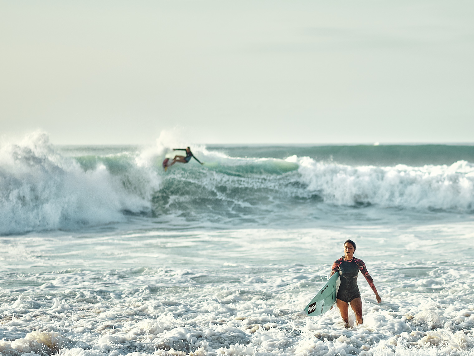 Kevin Steele - A young woman surfer emerges from big waves