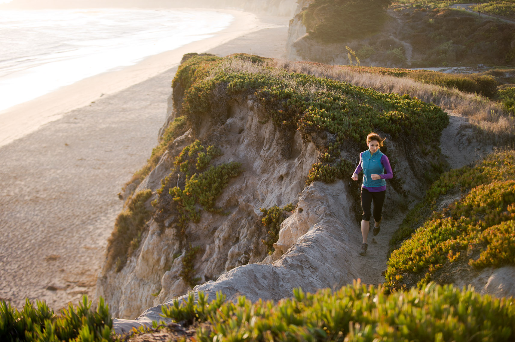 Kevin Steele - a woman running along a cliff above the ocean