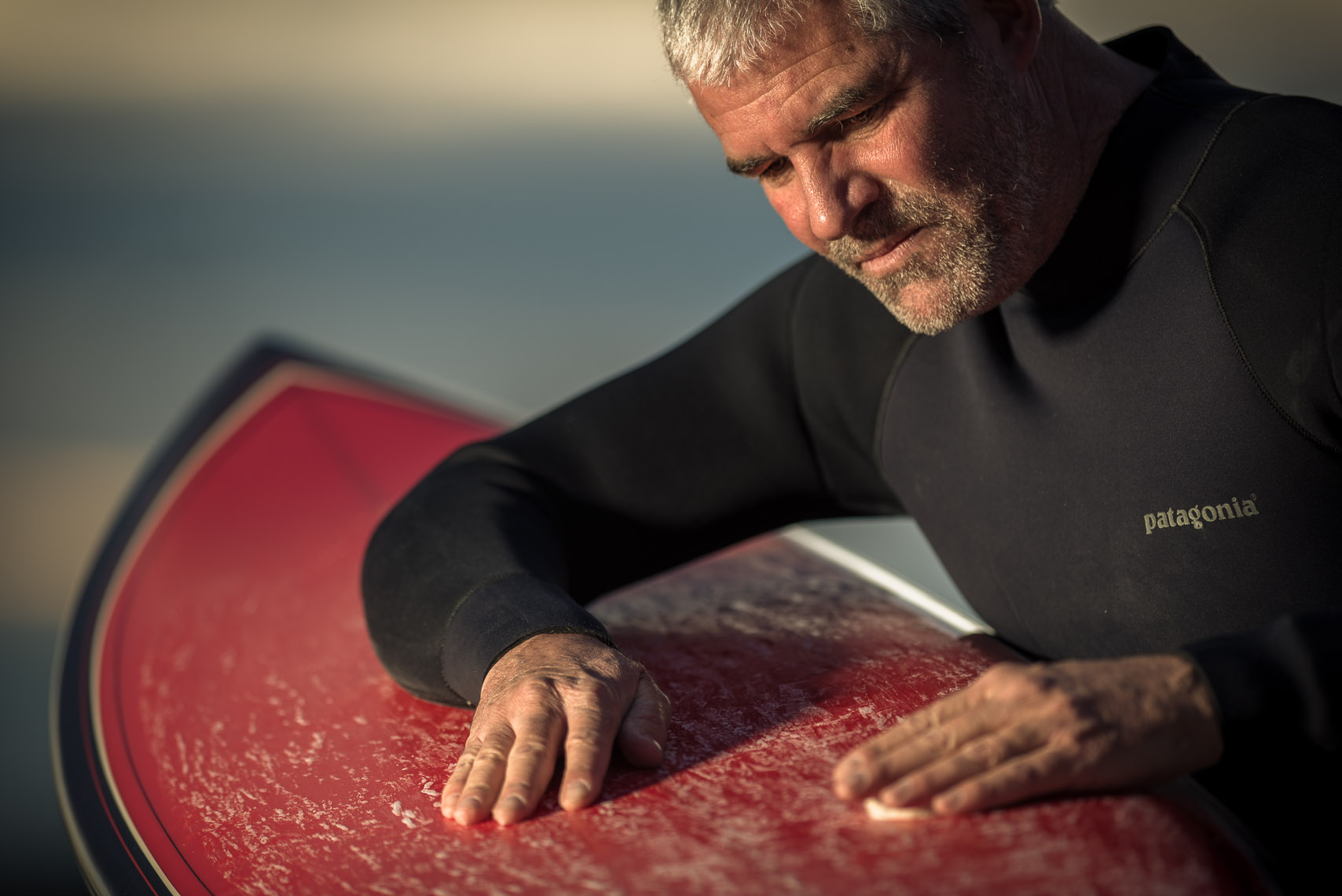 Kevin Steele - an elder surfer waxes his board at twilight